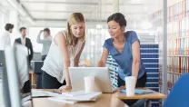 Two women looking at a laptop in office