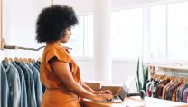 Female business owner using a laptop in her clothing store